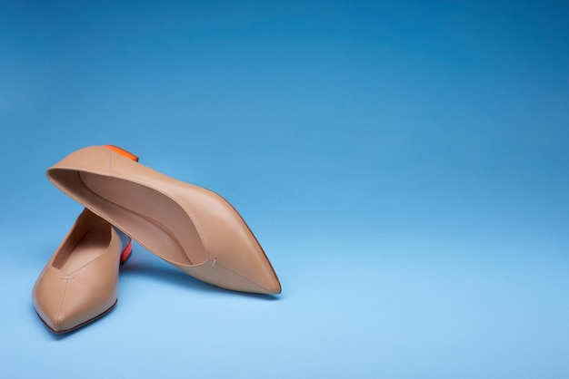 Chaussures de ballerine à la mode avec des orteils pointus et des talons bas orange vif isolés sur un fond bleu Une chaussure s'appuie sur une autre Copier l'espace pour le texte Capture de studio de chaussures à la mode