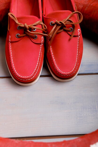 Chaussures bateau rouge sur fond en bois près de bouée de sauvetage. Vue de dessus. Fermer.