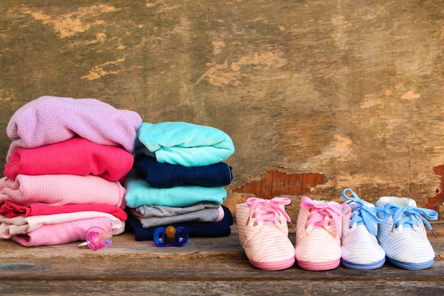 Chaussures bébé, vêtements et sucettes rose et bleu sur le vieux fond en bois.