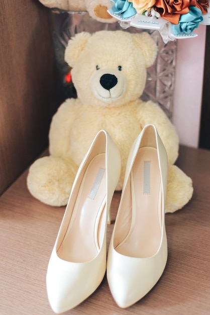 CHAUSSURES BLANCHES DE LA MARIÉE, OURS EN TEDDY BLANC, attributs de mariage en gros plan, attendant le mariage