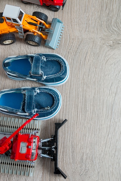 Chaussures bleues pour petit garçon près d'un ensemble de petites voitures