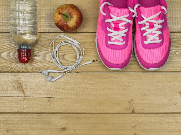 Chaussures de course roses pour les cours de fitness au gymnase et une pomme mûre sur un sol. Vue d'en-haut.