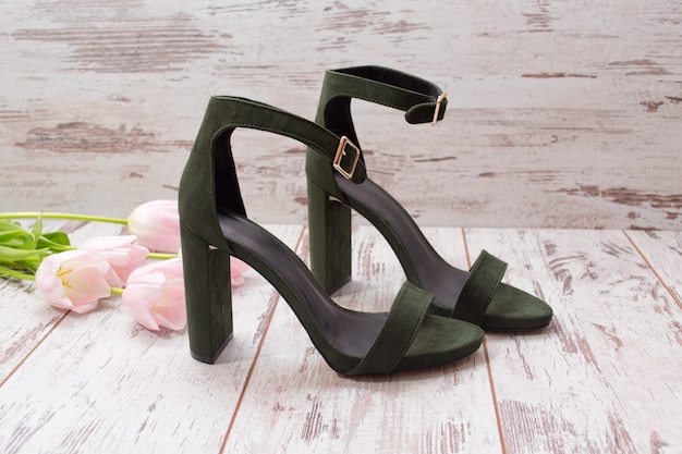 Chaussures en daim vert sur un plancher en bois, tulipes roses
