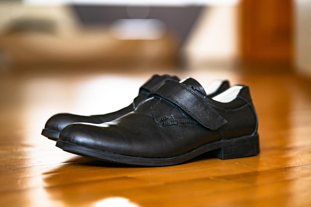 Chaussures d'école noires pour un garçon sur une surface en bois Le design contemporain porte quotidiennement des chaussures noires pour hommes sur le fond en bois