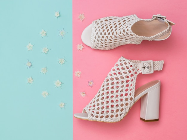 Photo chaussures d'été blanches pour femmes à la mode avec des fleurs sur une surface turquoise et rose