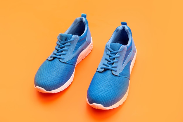 Chaussures sur fond orange. magasin de chaussures. concept de magasinage. chaussures pour l'entraînement. chaussures de sport pour la course. paire de chaussures de sport confortables. baskets bleues sportives.