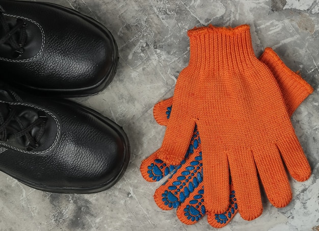 Chaussures et gants de travail en cuir sur fond de béton gris. Équipement de sécurité. Vue de dessus