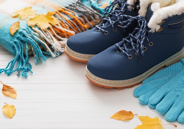 Chaussures d'hiver bleu et gants sur mur en bois blanc