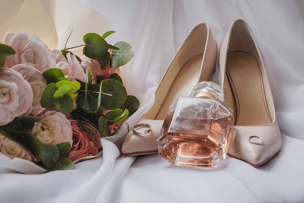 Chaussures de mariée avec bouquet de mariée et parfum sur le voile. Concept de mariage