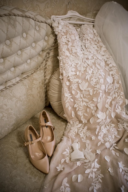 Les chaussures d'une mariée sont sur un lit avec une couverture blanche.