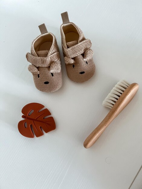 Chaussures marron pour enfants avec un museau et des oreilles une feuille de monstres et une brosse à cheveux de bébé sur fond blanc vue d'en haut flatley copie espace
