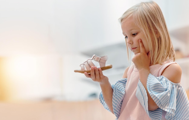 Chaussures et mode pour enfants avec une fille pensant à un choix dans un magasin de détail ou un centre commercial lors de ses achats Idée d'enfants et client avec une fille décidant d'acheter des chaussures avec une maquette