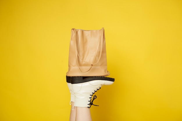 Les chaussures pour femmes blanches tiennent un sac beige sur un fond isolé jaune