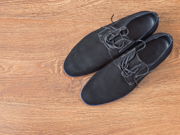 Chaussures pour hommes noirs sur un plancher en bois.