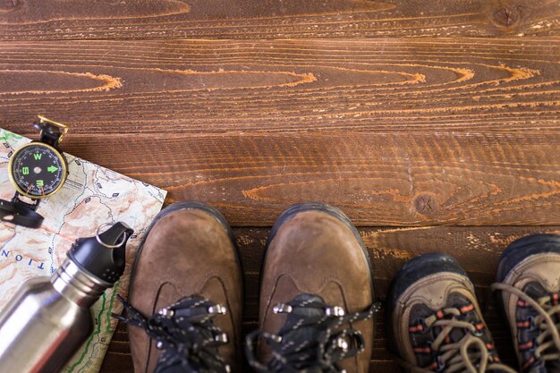 Chaussures de randonnée avec carte topographique et boussole sur fond de bois.