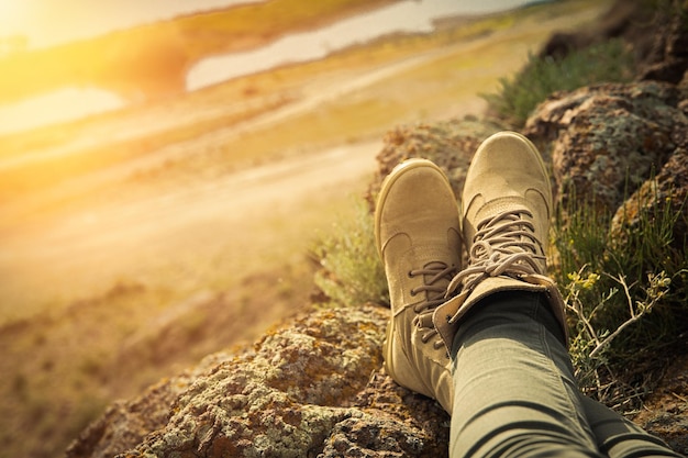 Photo chaussures de randonnée marron à lacets hauts sur les jambes féminines dans un style safari en terrain rocheux espace de copie