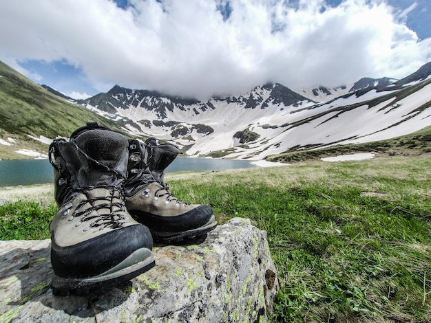 Des chaussures sur le rocher par les montagnes contre le ciel