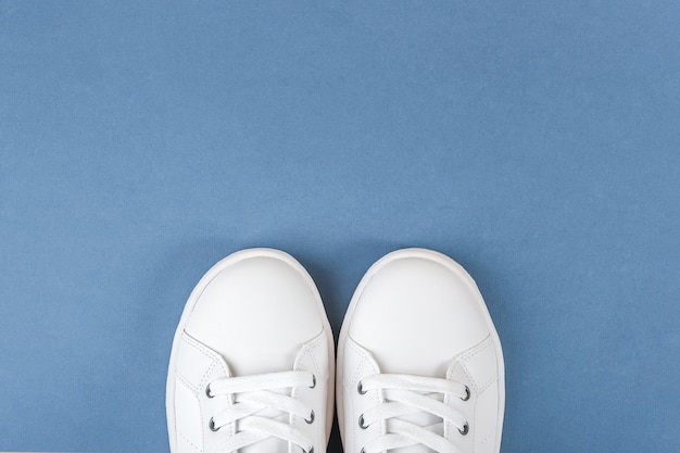 Chaussures de sport blanches, baskets avec lacets sur bleu