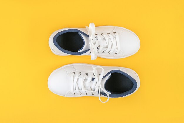 Chaussures de sport blanches, baskets à lacets sur fond jaune. Concept de style de vie sportif