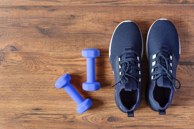 Chaussures de sport et haltères sur la vue de dessus de fond en bois Concept d'entraînement de remise en forme