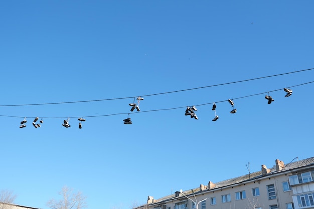 Des chaussures de sport sont suspendues à des fils. Des baskets suspendues par des lacets à des fils électriques.