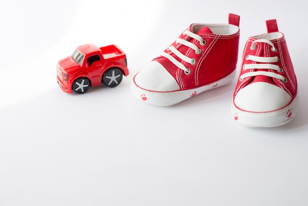 Chaussures de toile rouge de petite taille mignons avec vue de dessus de voiture jouet blanc avec fond