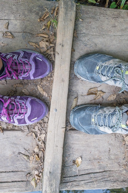 chaussures de trekking féminines devant des chaussettes de trekking masculines sur un pont en bois dans la nature