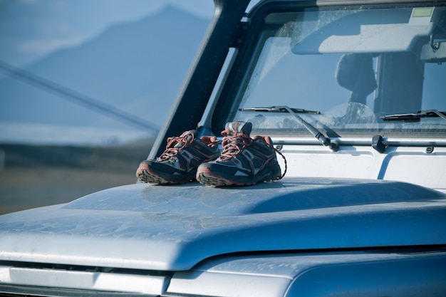 Les chaussures de trekking sèchent sur un capot de voiture 4x4 sale