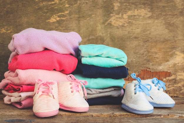 Chaussures, vêtements et sucettes bébé roses et bleus sur le vieux fond en bois. Image tonique.