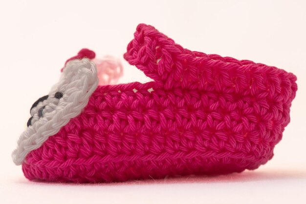 Chaussures avec des visages pour un nouveau-né au crochet sur fond blanc