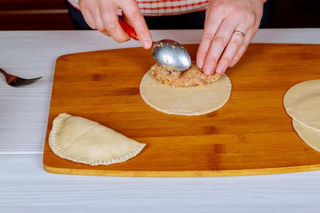 Chebureks cuisiner à la maison non rôti cheburek avec de la farine sur une planche de bois un seul morceau rond de pâte