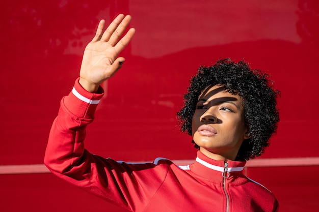 Cheerful African American Woman in sportswear sur fond rouge par une journée ensoleillée