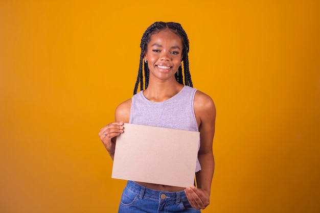 Cheerful afro american woman montrant tableau blanc sur fond jaune