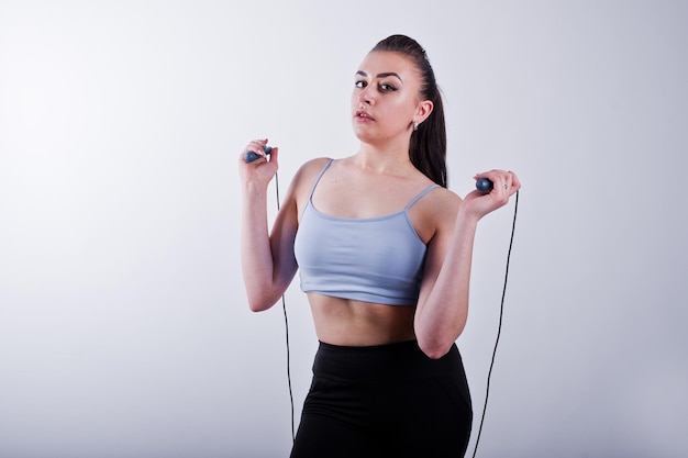 Cheerful attractive young fitness woman in top et leggings noirs avec corde à sauter isolé sur fond blanc