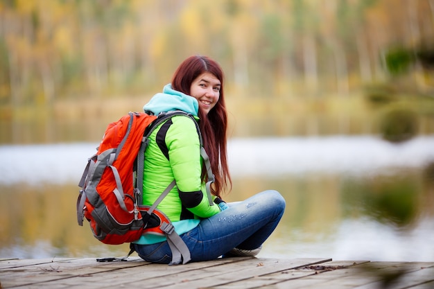 Cheerful brunette sitting avec sac à dos au lac