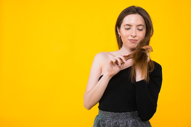 Cheerful cheery lady holding in hand comb fermeture visage lisse doux effet cheveux soyeux kératine