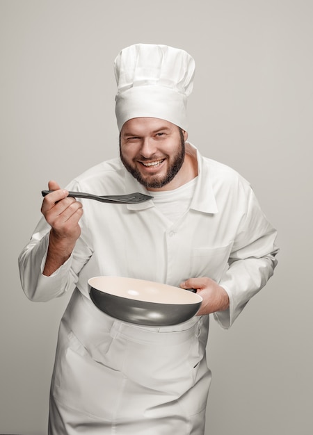 Cheerful chef dégustation de plats de la poêle