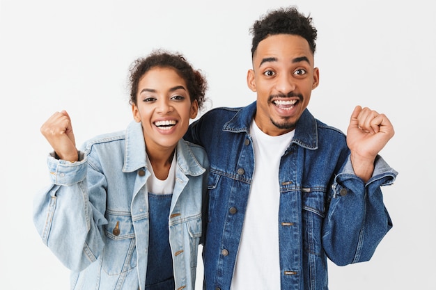 Cheerful couple africain en chemises en denim se réjouit ensemble sur mur gris