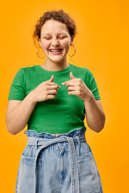 Cheerful girl in a green tshirt posant geste mains fond jaune