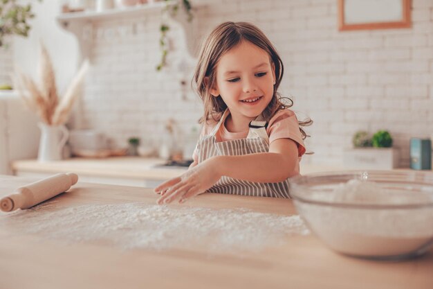 Cheerful girl s'amusant avec de la farine sur la table de la cuisine