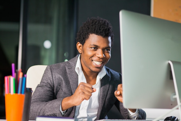 Cheerful guy man look heureux au moniteur employé de bureau indépendant entrepreneur prospère