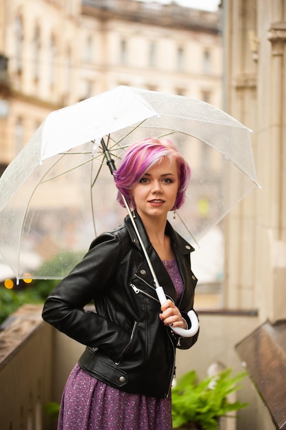 Cheerful jolie fille tenant un parapluie tout en se promenant à l'extérieur Elle fait demi-tour et regarde ca