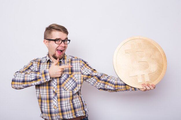 Cheerful man holding gold bitcoin - crypto-monnaie populaire, argent virtuel.