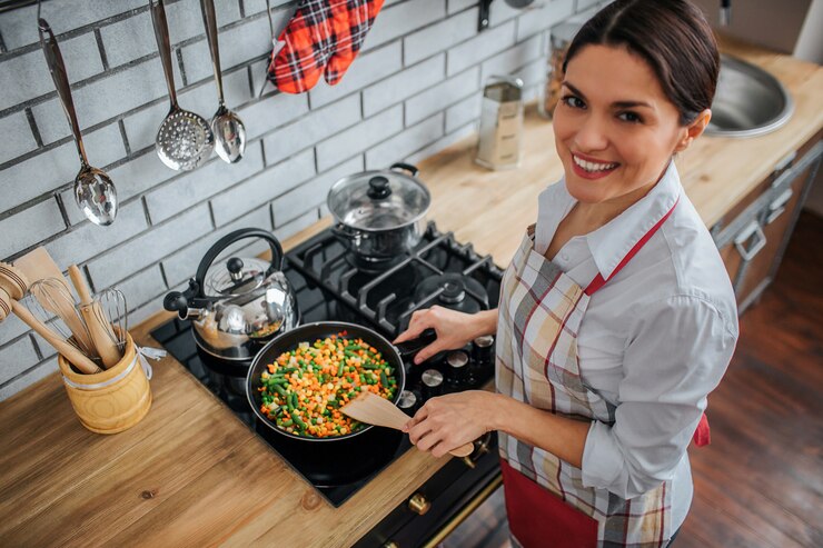 Photo cheerful nice adult woman stand in kitchen at cuisinière.