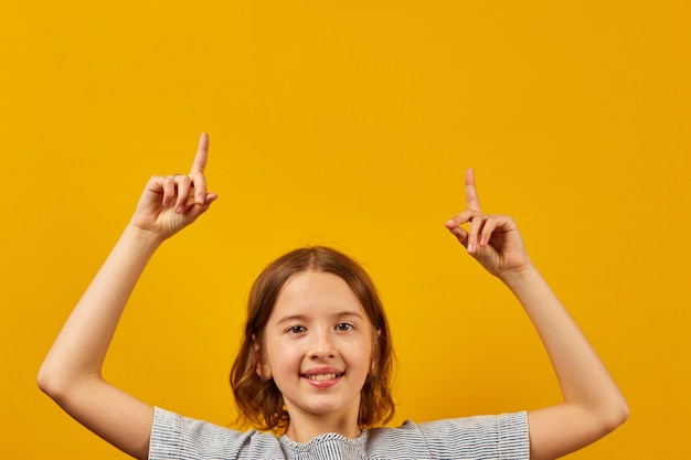 Cheerful positive dix ans adolescente pointant les doigts vers le haut