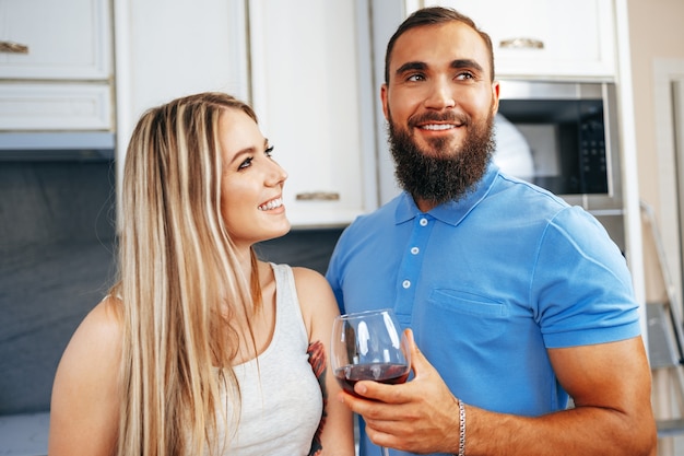 Cheerful smiling couple cuisine et boire du vin dans la cuisine à la maison