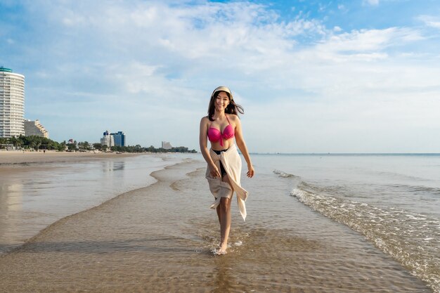 Cheerful woman in bikini marchant sur la plage de la mer