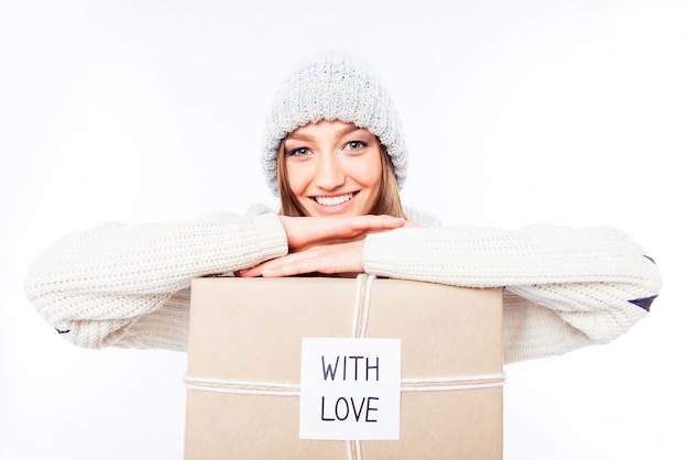 Cheerful woman in hot hat et écharpe avec package féliciter avec Noël