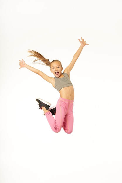 Cheerful woman in sportswear sautant en l'air et levant les bras. Isolé sur fond blanc