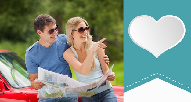 Photo cheerful young couple reading map contre heart label